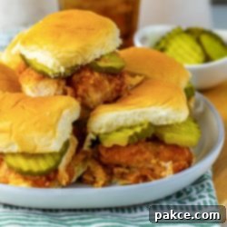 Sweet Heat Chicken Sliders in a Snap 12 A pile of hot honey chicken sliders with pickles on a plate.