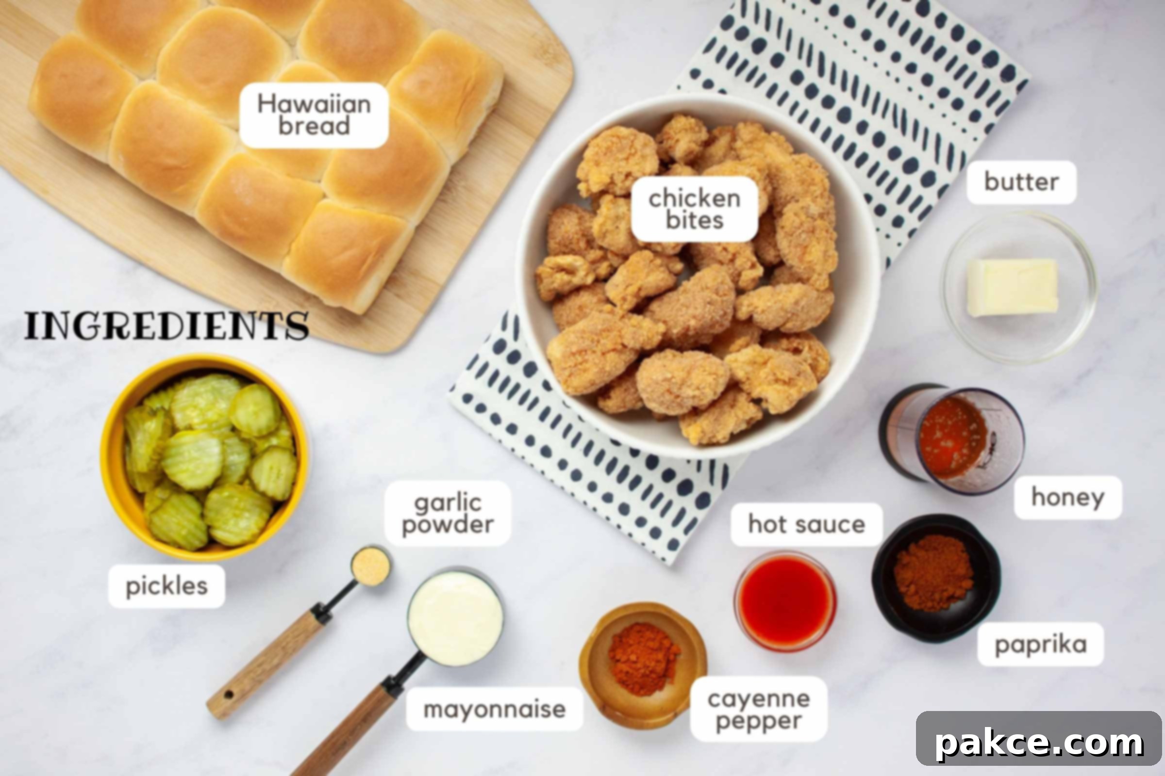 Sweet Heat Chicken Sliders in a Snap 3 Ingredients on a counter: Frozen chicken bites, butter, honey, paprika, hot sauce, cayenne pepper, mayonnaise, garlic powder, pickles, and Hawaiian bread.
