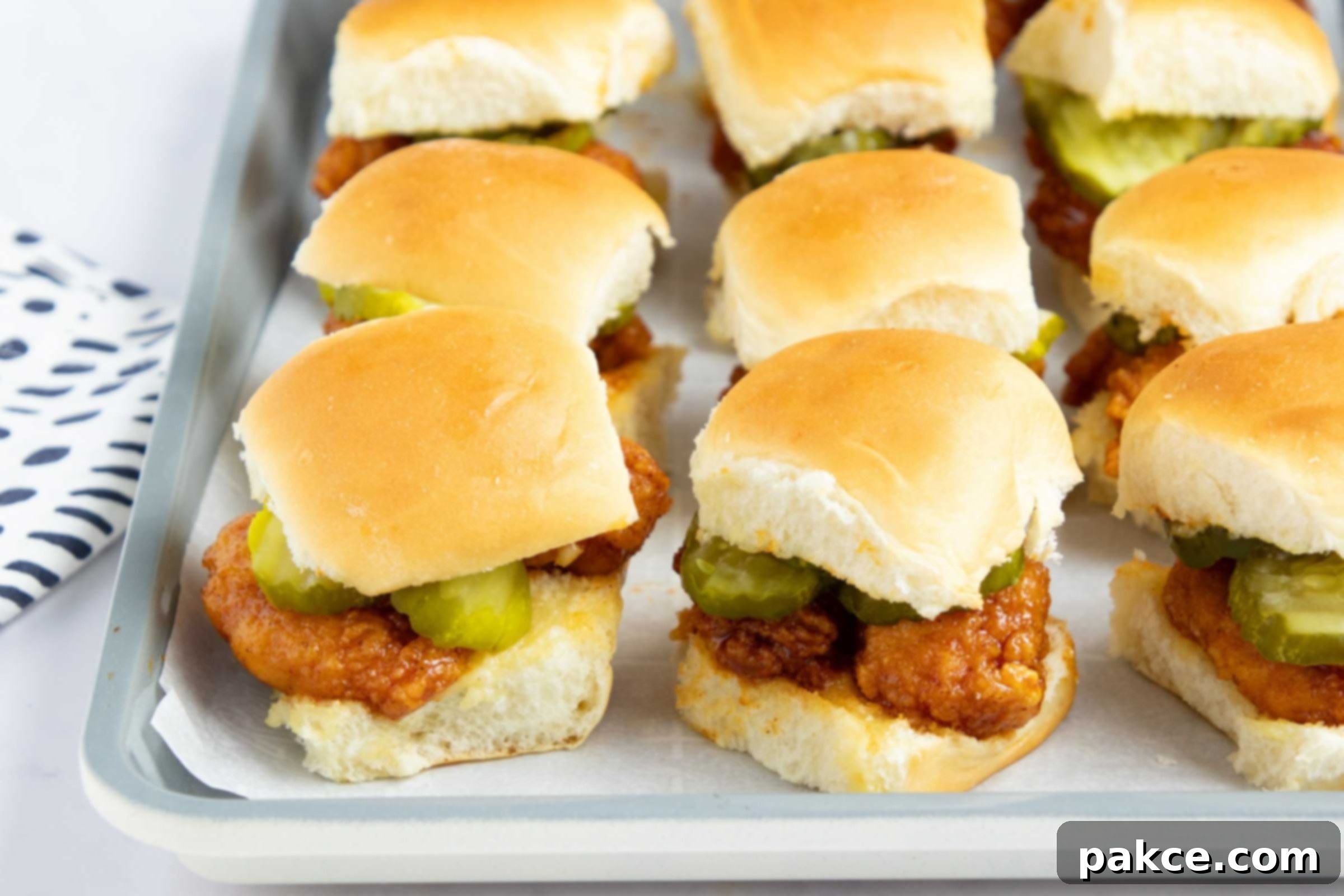 Sweet Heat Chicken Sliders in a Snap 10 Hot honey chicken sliders with pickles on a baking sheet.
