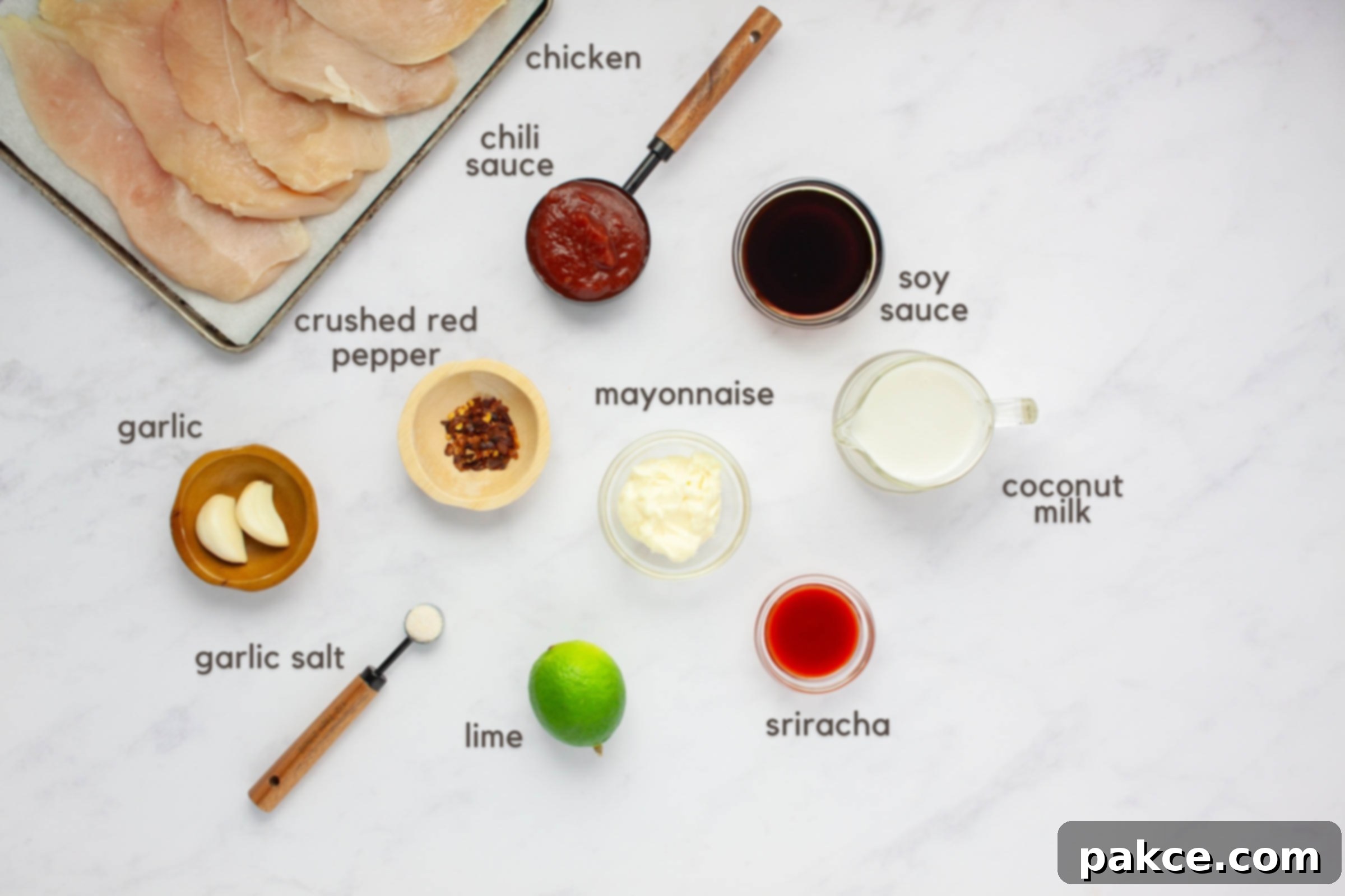 Spicy Chili Lime Chicken with Creamy Coconut Lime Sauce 3 Labeled ingredients on a counter: boneless, skinless chicken breasts, chili sauce, soy sauce, crushed red pepper, garlic cloves, garlic salt, lime, mayonnaise, sriracha, and coconut milk.