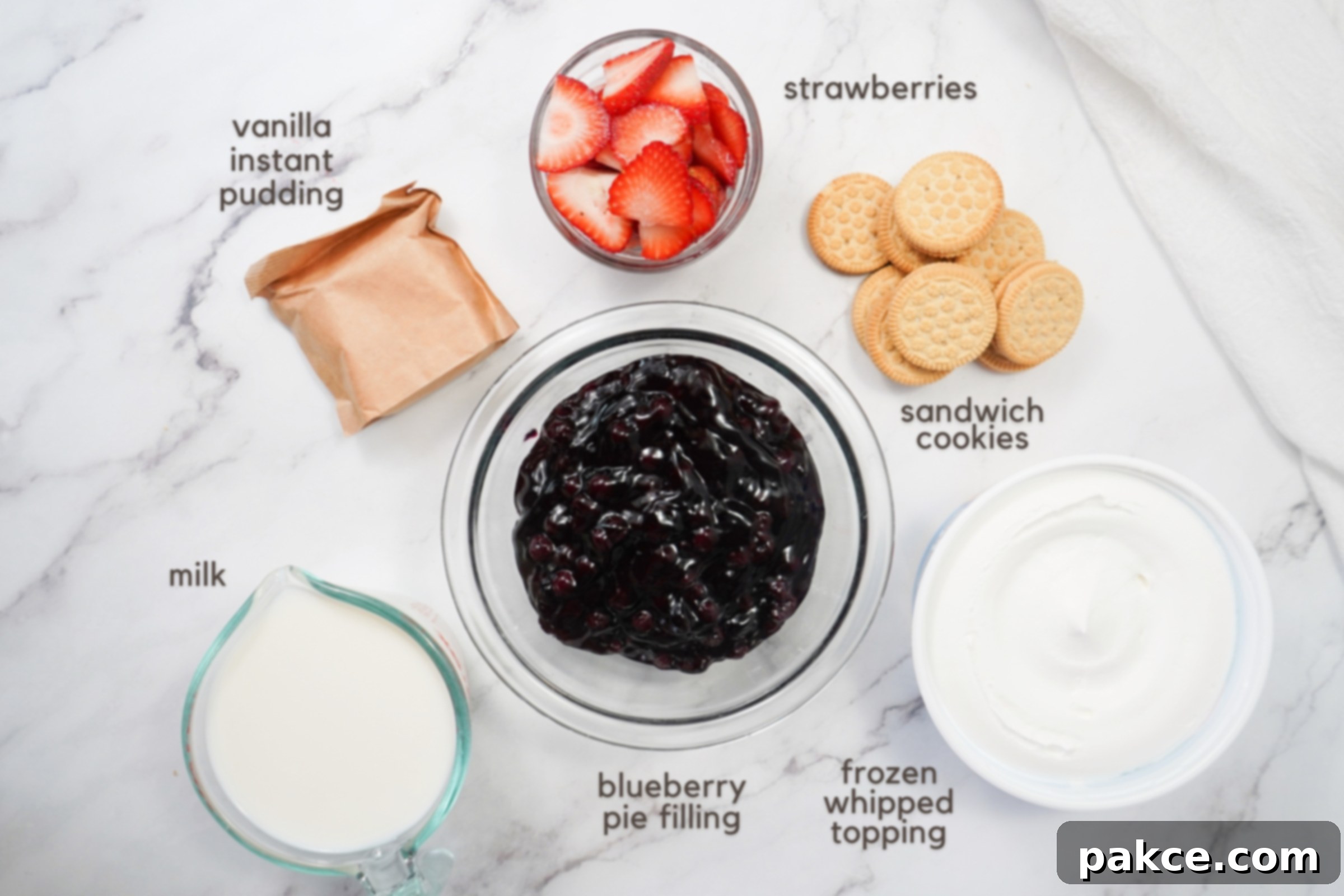 Red White and Blue Celebration Cups 3 Labeled ingredients on a counter: Vanilla instant pudding mix, sliced strawberries, sandwich cookies, milk, blueberry pie filling, and frozen whipped topping.
