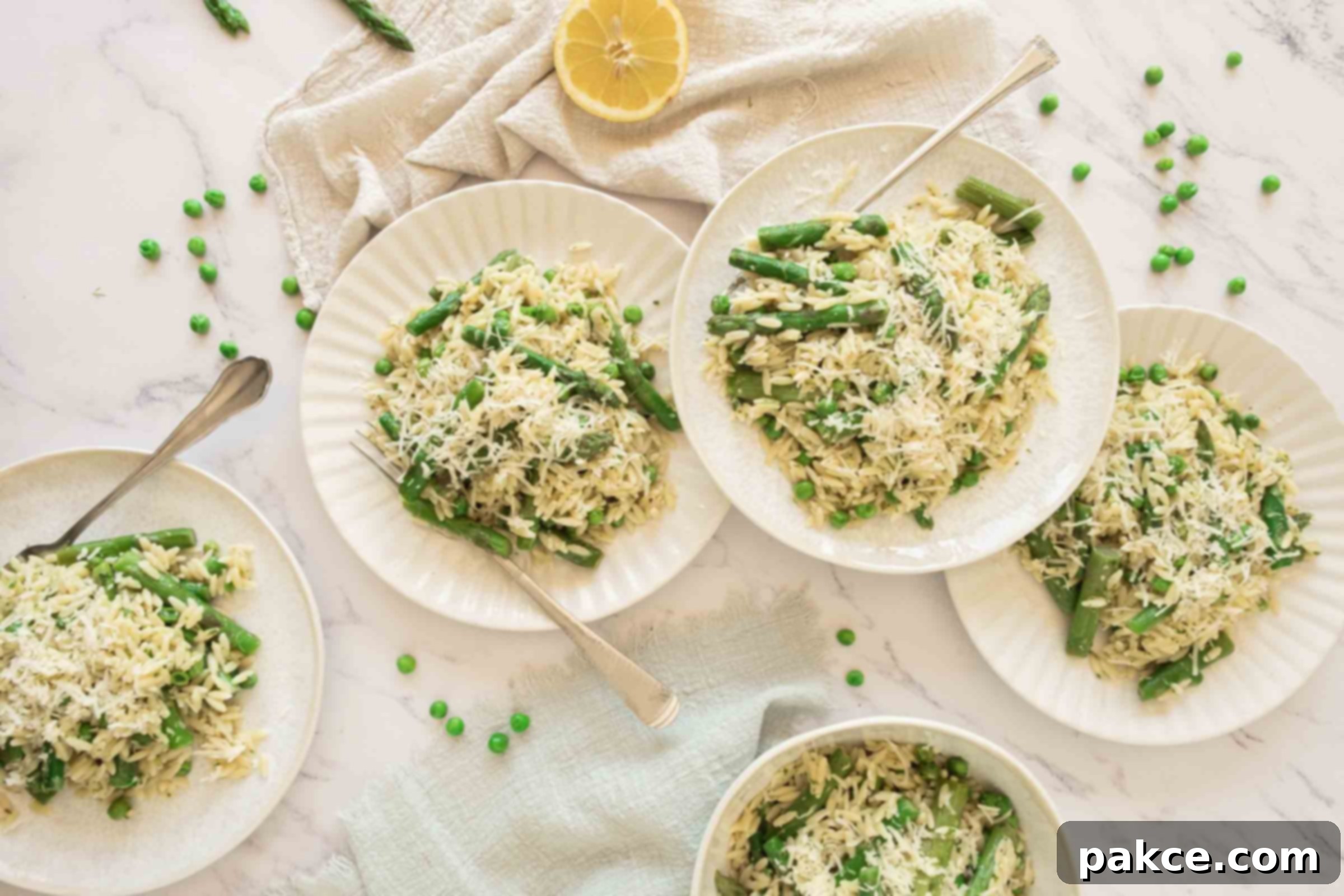 Zesty Orzo Pasta with Spring Greens and Parmesan 5 Plates of lemon orzo with peas and asparagus on a counter beside a half-cut lemon, emphasizing freshness.