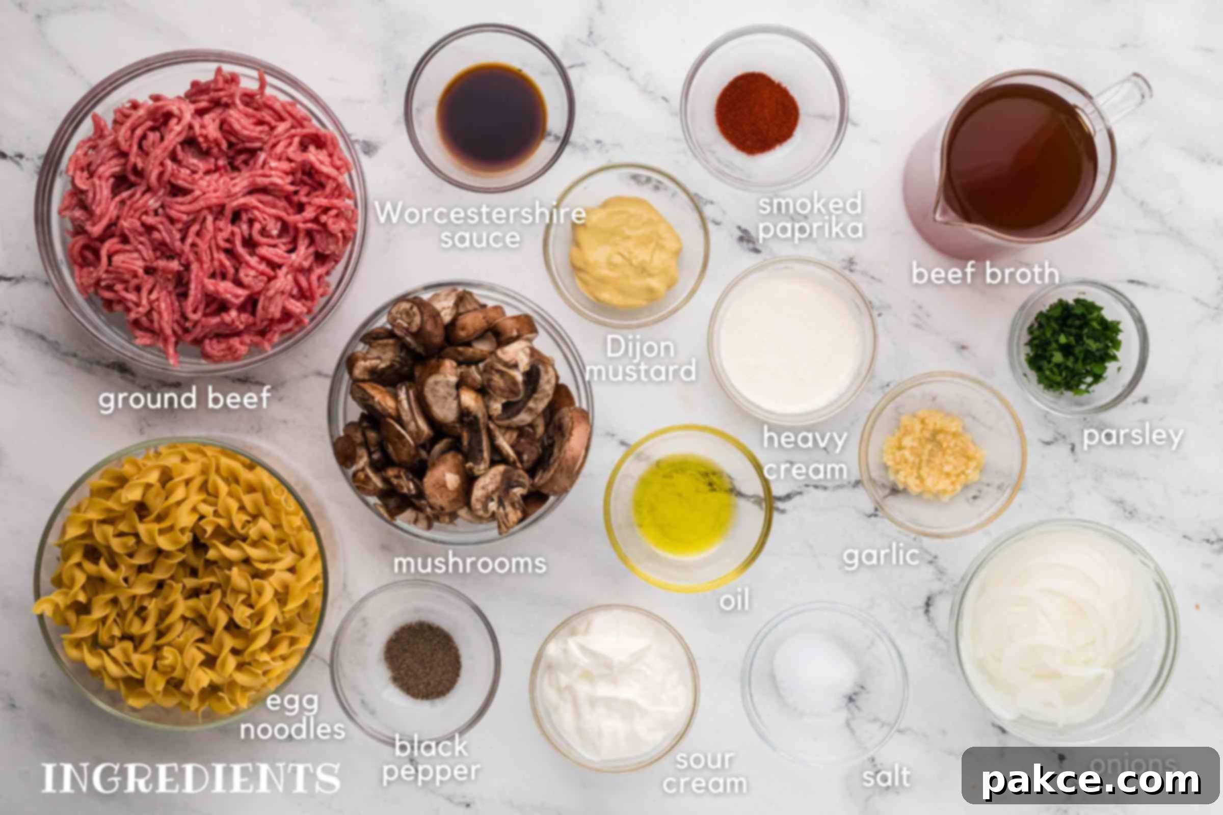 Quick and Creamy One-Pot Ground Beef Stroganoff 3 Labeled photo of ingredients: ground bee, egg noodles, mushrooms, dijon mustard, smoked paprika, beef broth, heavy cream, minced garlic, parsley, onions, sour cream, oil, salt, and pepper.