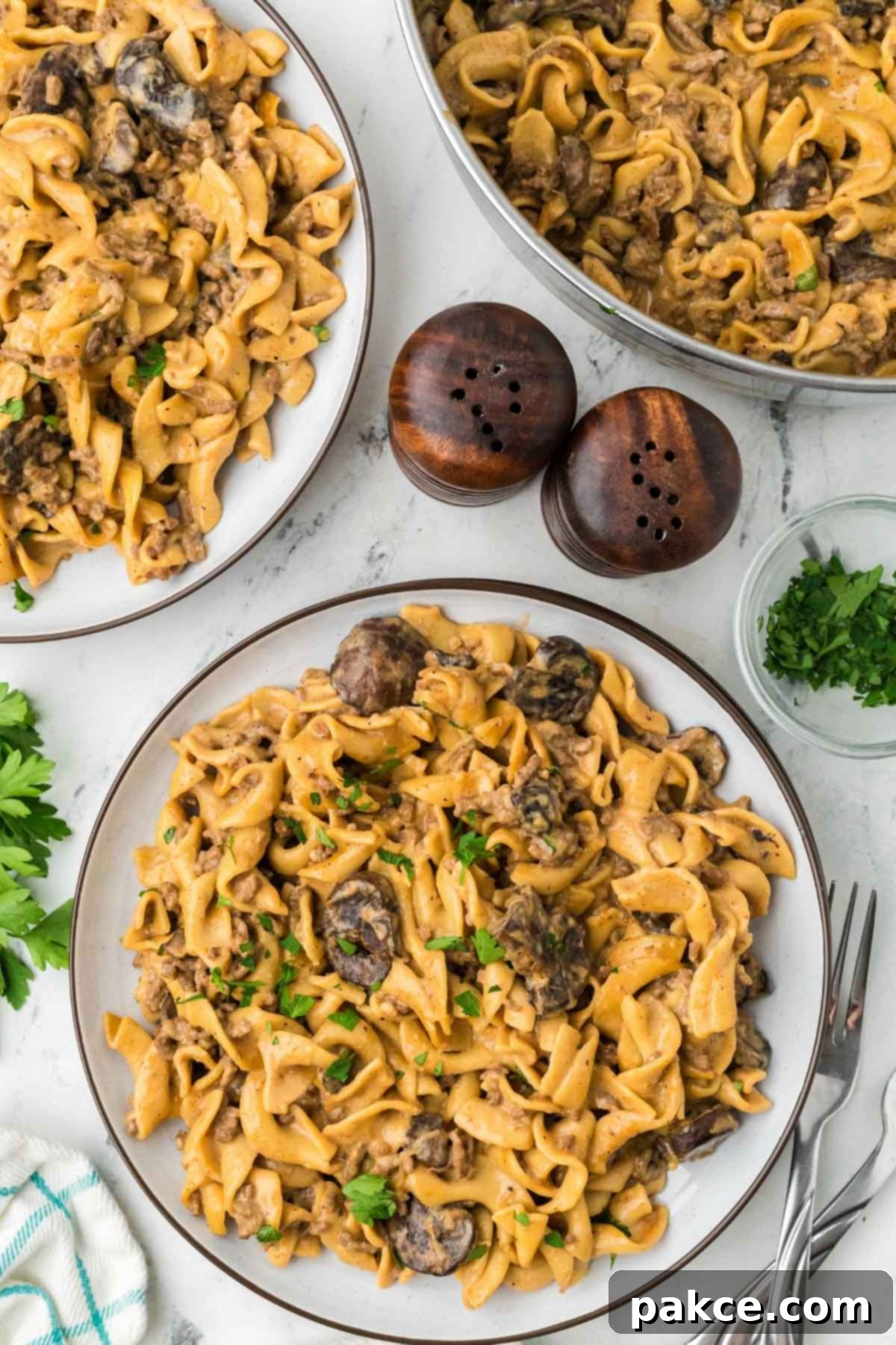 Quick and Creamy One-Pot Ground Beef Stroganoff 9 Two plates of ground beef Stroganoff with mushrooms beside a pot of the same.