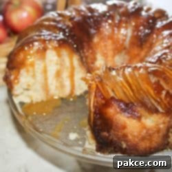 Caramelized Apple Bundt Inversion 11 A close-up shot of the Caramel Apple Upside Down Bundt Cake, with a slice removed to reveal its tender apple-filled interior and a generous amount of caramel sauce cascading down its golden-brown crust. This tempting image highlights the cake's autumnal flavors and perfect texture, making it an irresistible fall dessert.