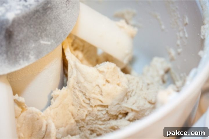 Easy Homemade Buttermilk Biscuits Stand mixer with dough paddles and biscuit dough being mixed