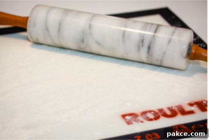 homemade-buttermilk-biscuits-ip-2-min Silicone mat with flour sprinkled on it and a marble rolling pin to the side