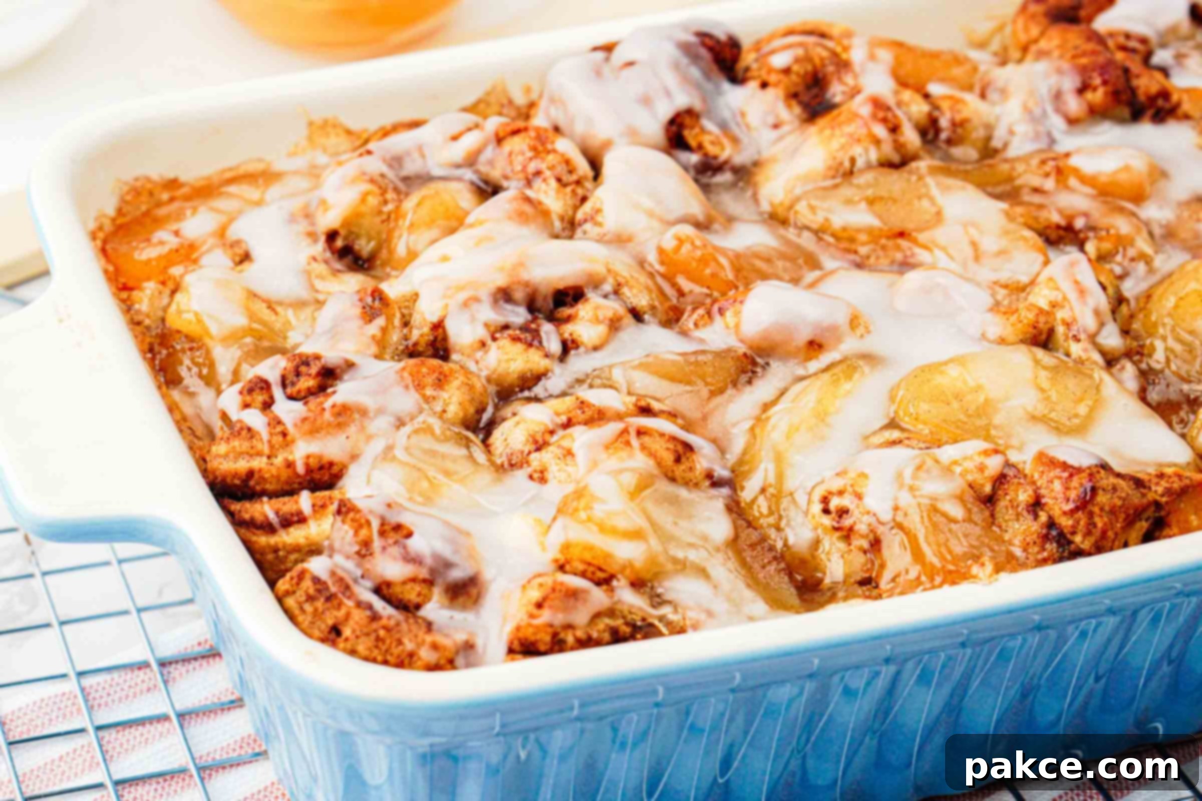 Warm apple cinnamon roll bake drizzled with sweet glaze in a baking dish, ready to serve.