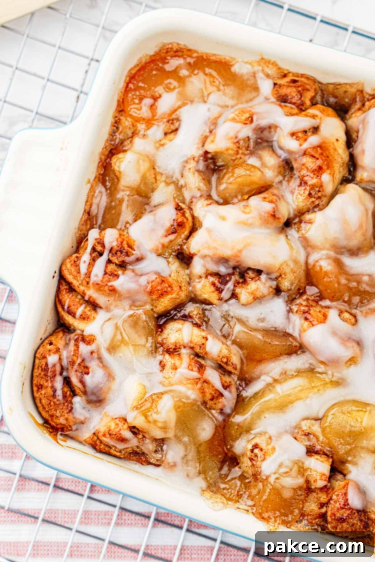 Close-up of baked apple cinnamon roll casserole with glaze, showcasing the golden-brown crust and gooey texture.
