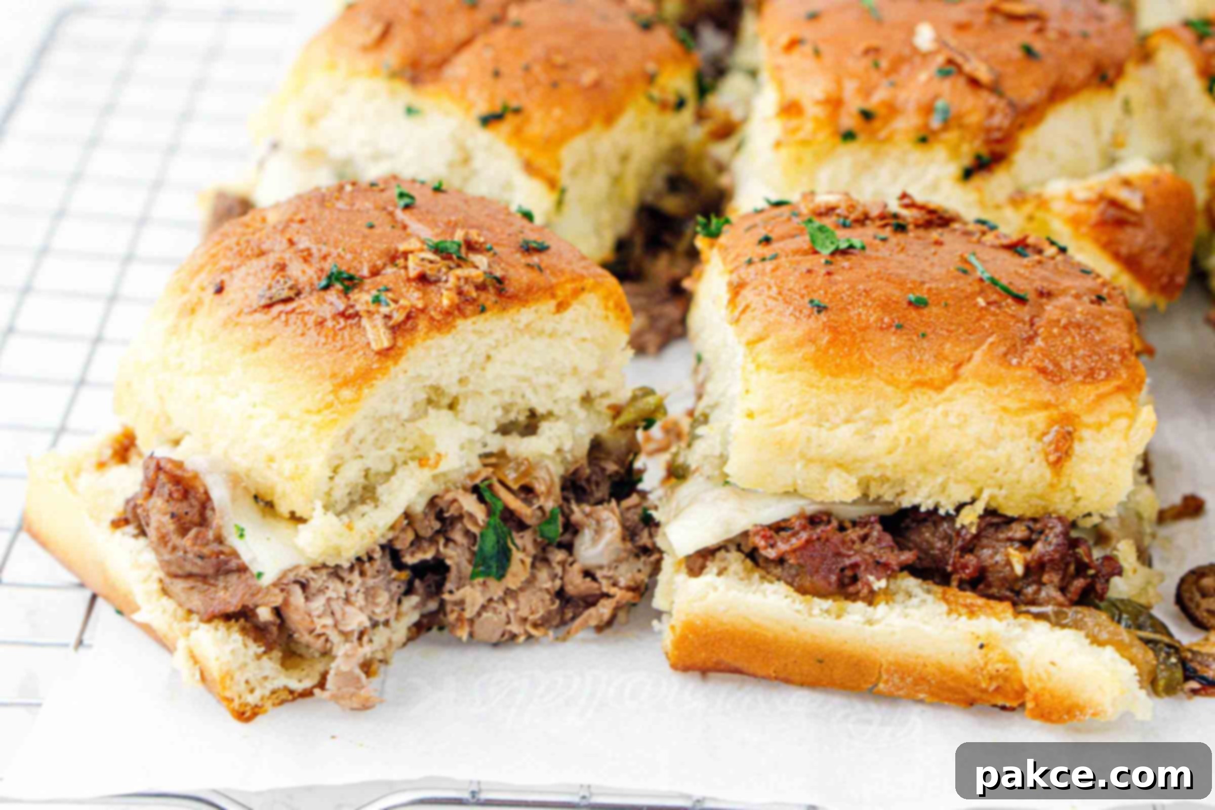 Philly cheesesteak sliders on parchment paper after baking, ready to be served.
