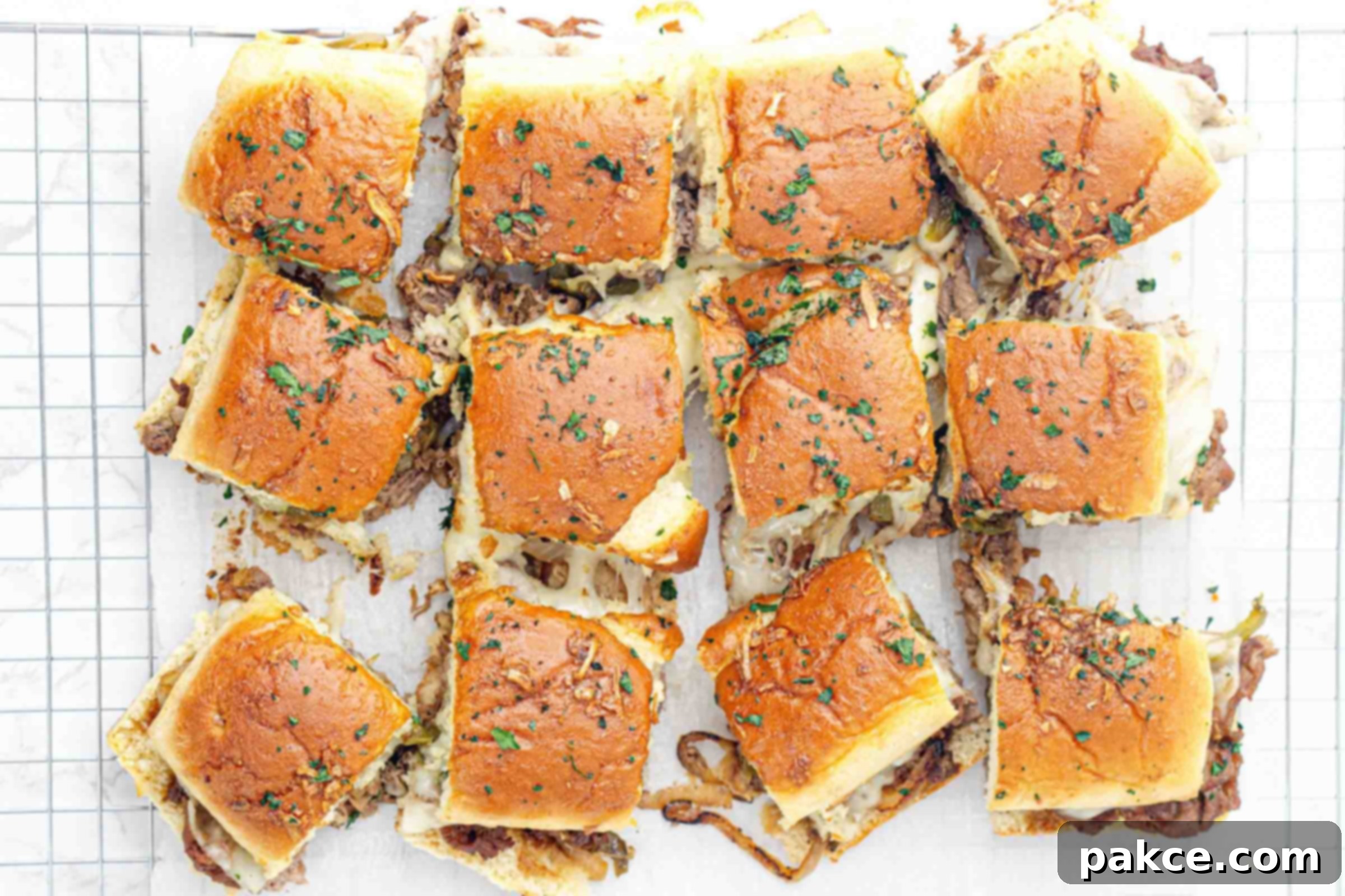 Philly cheesesteak sliders baked and resting on parchment paper.