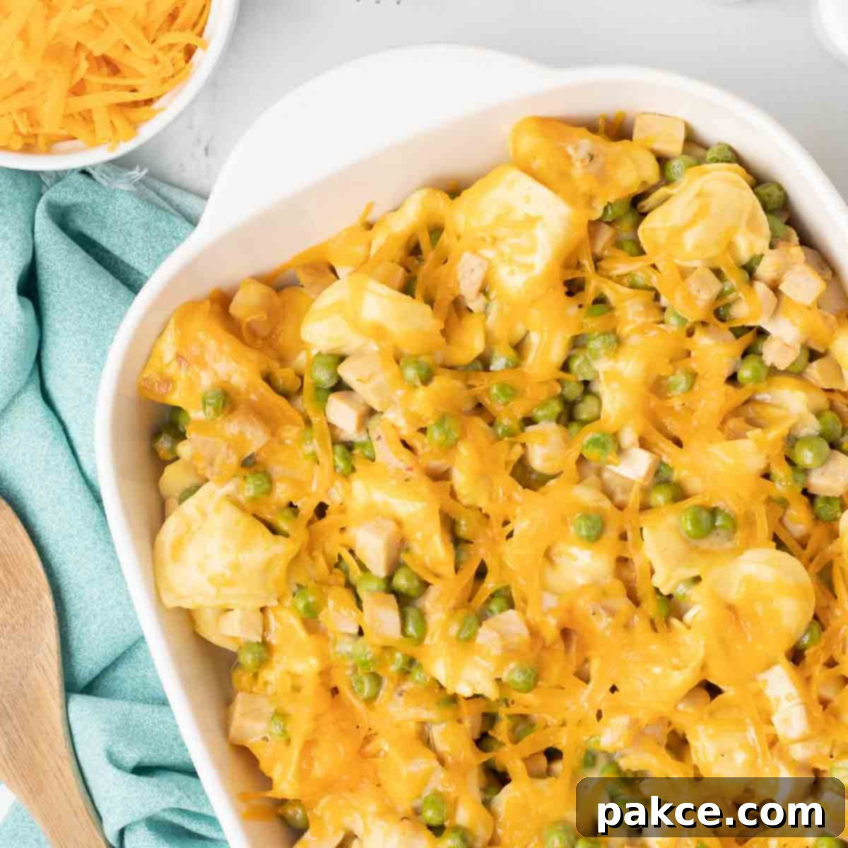 Tortellini, leftover turkey, and peas in a cheesy casserole, bubbly and golden brown, ready to be served from a baking dish.