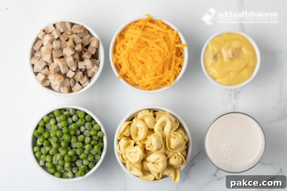 Creamy Turkey Tortellini Bake 3 Key ingredients laid out for Leftover Turkey Tortellini Casserole: a can of condensed cream of chicken soup, a package of cheese tortellini, a bag of frozen peas, a block of shredded sharp cheddar cheese, cooked leftover turkey, and a carton of milk.