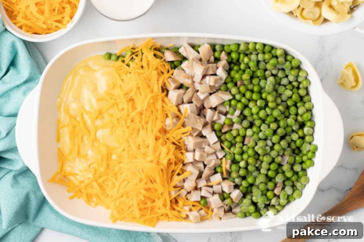 Creamy Turkey Tortellini Bake 5 Condensed cream of chicken soup, shredded sharp cheddar cheese, chopped leftover cooked turkey, and frozen peas arranged in a glass casserole dish before being mixed together for the base of the casserole.