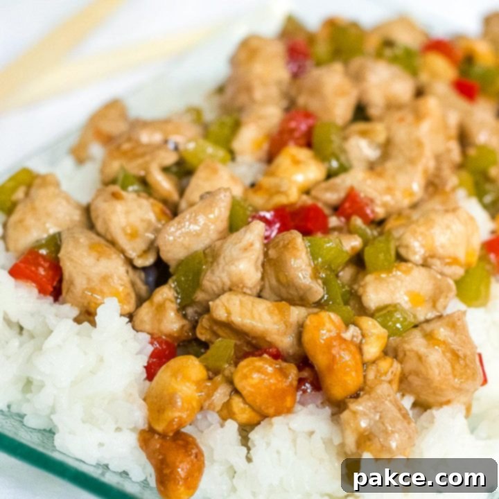 Diced chicken and diced red and green bell peppers on a bed of rice on a transparent square glass plate.