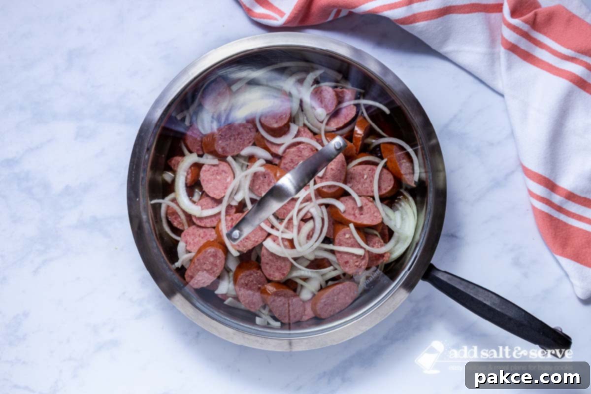 Brown Sugar Kielbasa Skillet 5 A covered skillet with sliced kielbasa and onions simmering in a brown sugar and apple cider vinegar syrup.