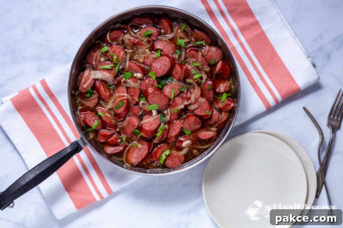 Brown Sugar Kielbasa Skillet 7 Close-up of cooked brown sugar kielbasa in a skillet, ready to be served, with a vibrant green parsley garnish.