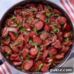 Brown Sugar Kielbasa Skillet 8 Cooked brown sugar kielbasa in a skillet, glistening with a rich glaze and caramelized onions.