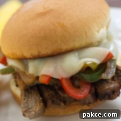 Sizzling Steak and Pepper Melts 3 Close up photo of Steak Sandwich with Cheese and Peppers on a white plate