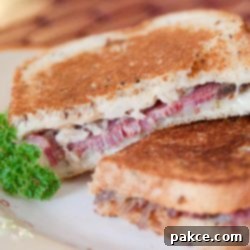 The Ultimate Reuben Sandwich 3 Two Reuben sandwiches on a white plate.