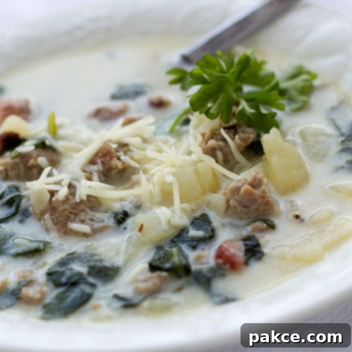 Bowl of Zuppa Toscana soup with spinach, potatoes, crispy turkey bacon, and a sprinkle of Parmesan cheese
