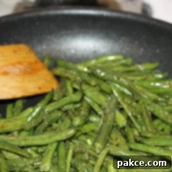 Flavorful Green Beans 4 Sautéed seasoned green beans in a black frypan
