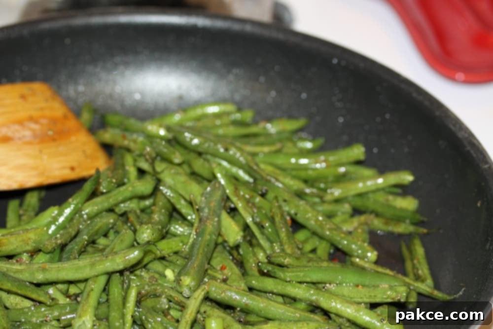 Green Beans Seasoned with Italian Dressing Sautéed seasoned green beans in a black frypan