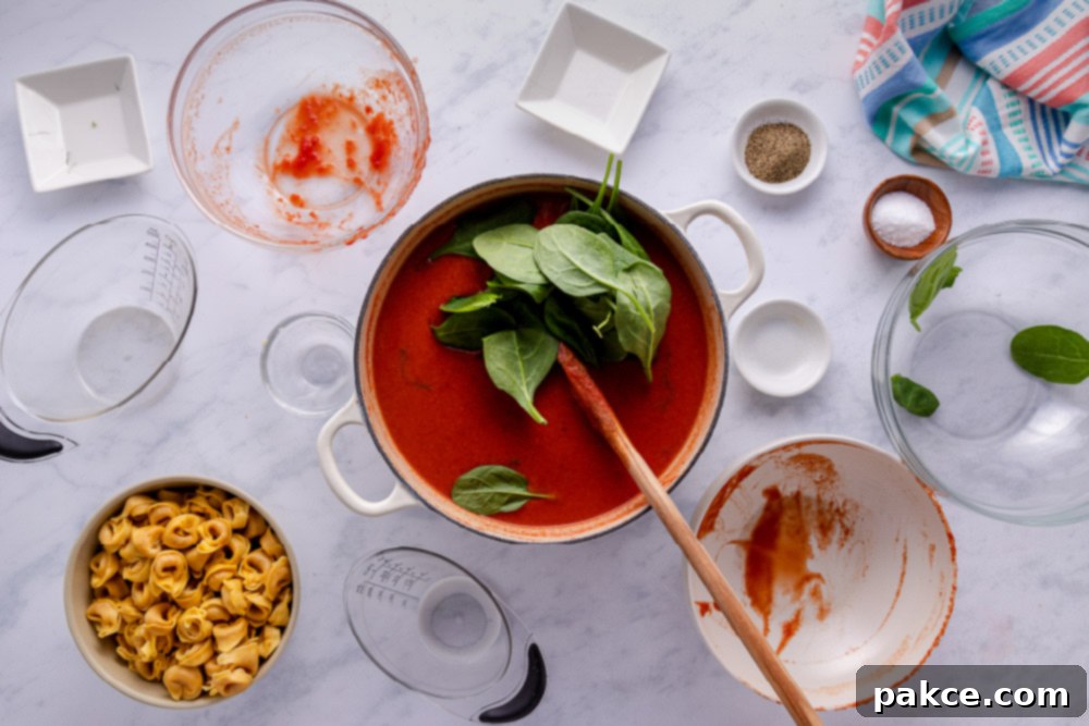 Adding fresh spinach to the hot Tomato Spinach Tortellini Soup