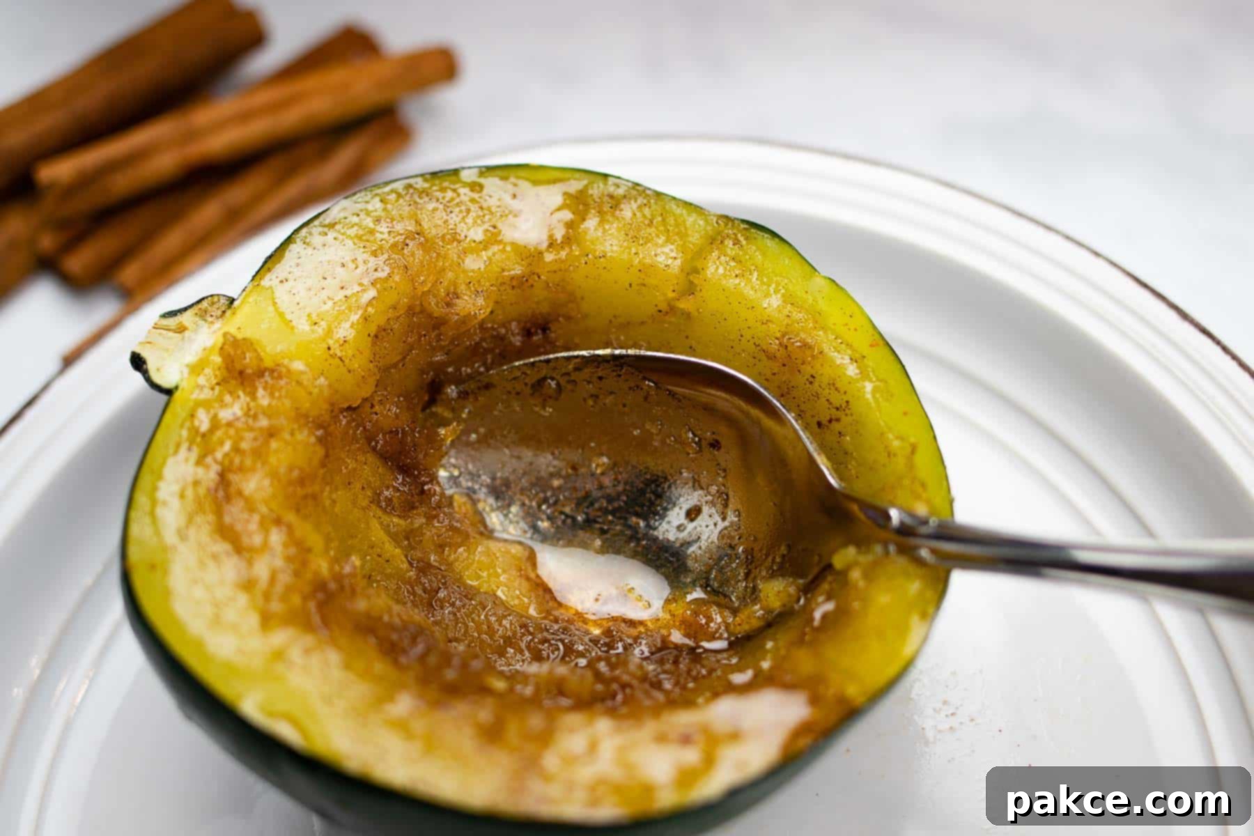 Plate of acorn squash with butter, brown sugar and cinnamon with spoon.