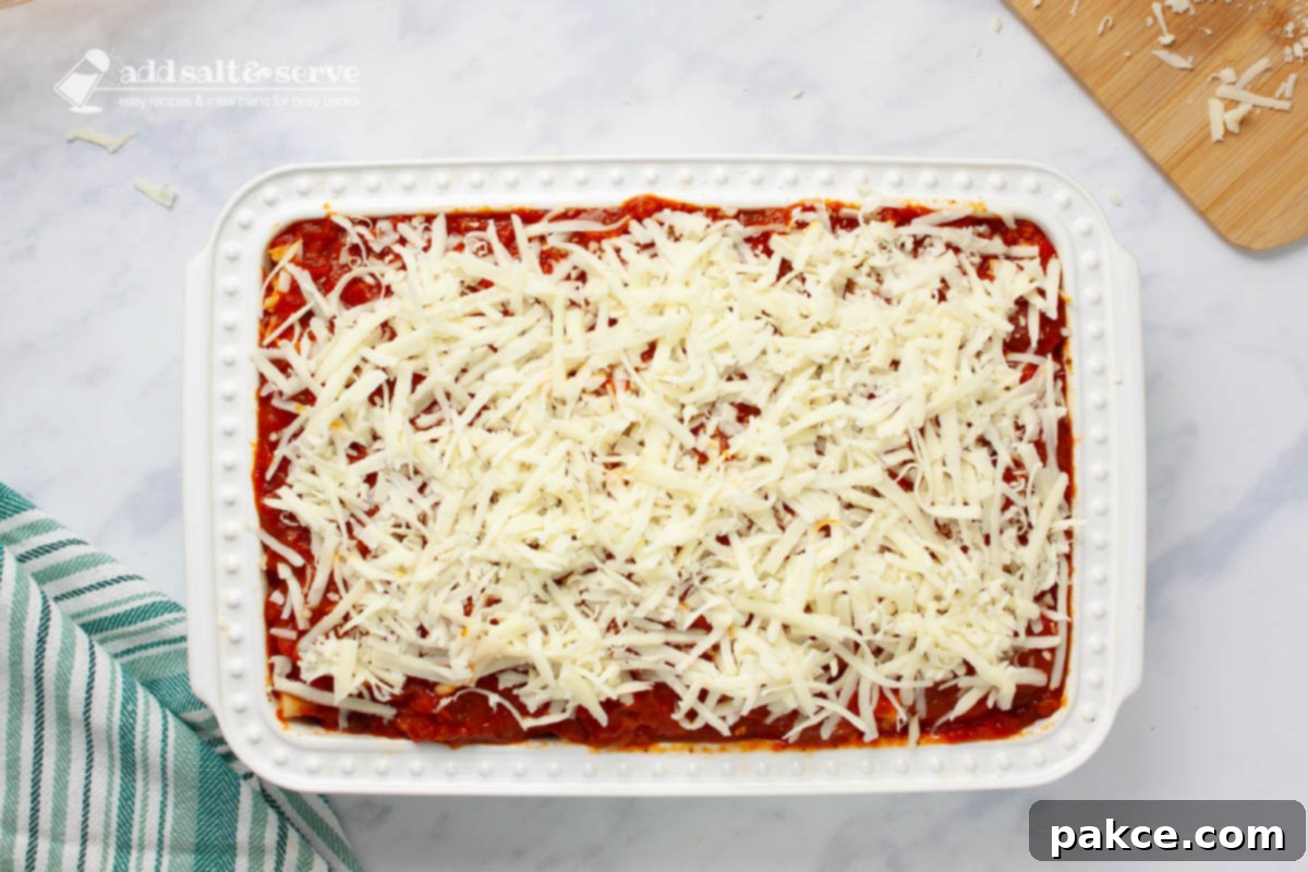 Classic Cheesy Meatless Baked Ziti 7 Baking pan showing mozzarella cheese layered over marinara sauce for baked ziti.