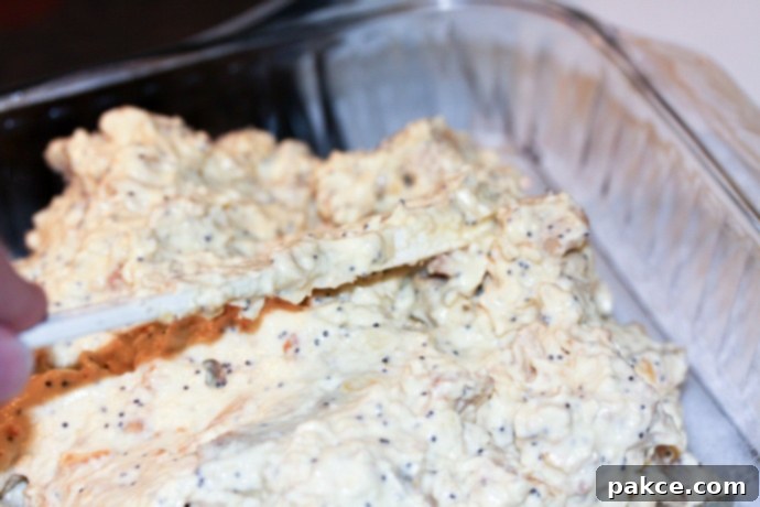 Spreading poppy seed chicken mixture in pan