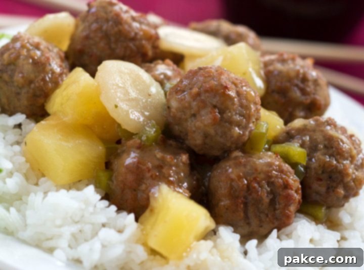Meatballs, water chestnuts, and pineapple chunks in sauce over white rice, text Sweet and Sour Meatballs #quickandeasy