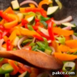 Vibrant Wok Vegetables 2 colorful vegetables in a pan with a wooden spoon stirring