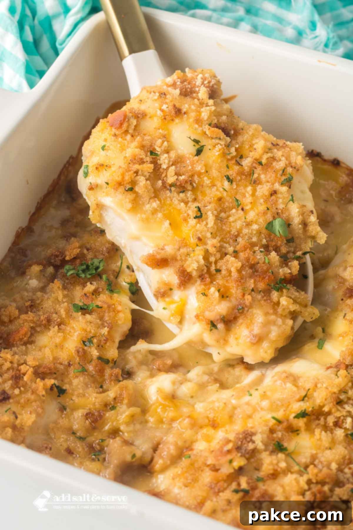 Baked Swiss Chicken Swiss chicken with white wine and stuffing in a casserole dish with a serving spoon lifting a serving out.