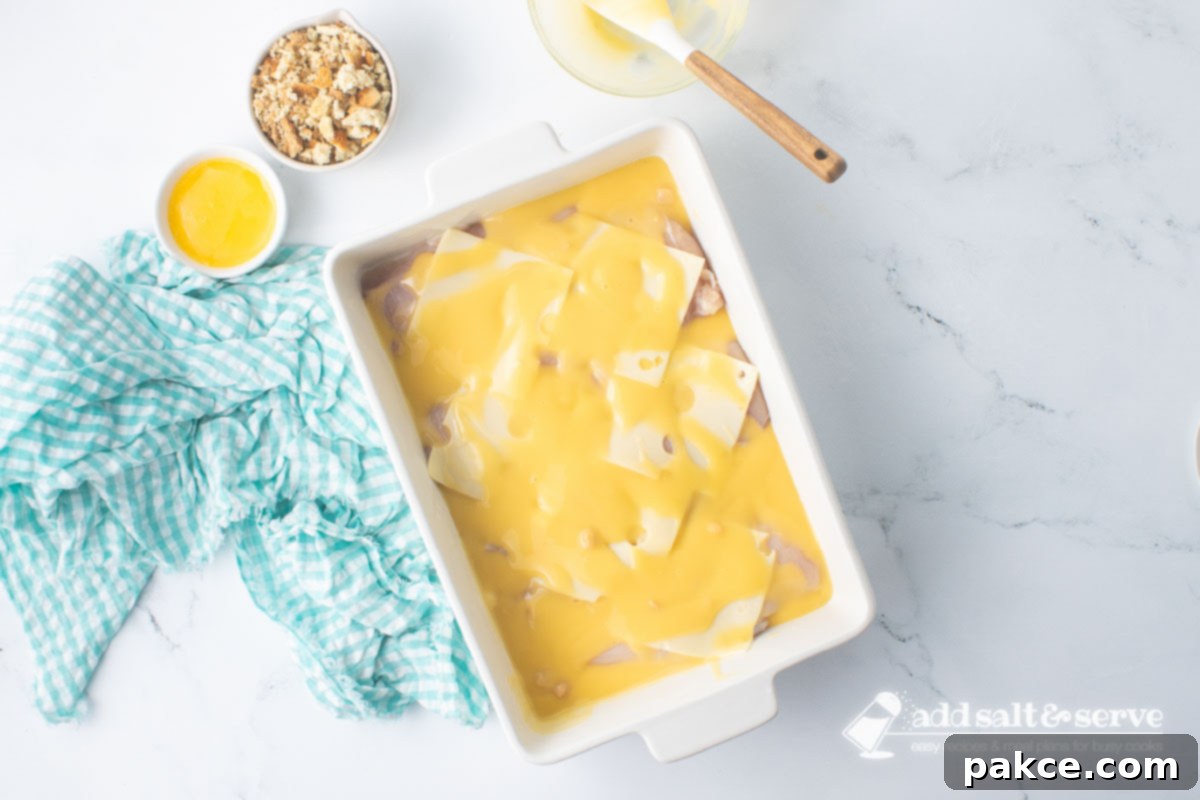 Baked Swiss Chicken with White Wine 7 Casserole dish of chicken breasts and Swiss cheese with white wine sauce before adding stuffing and melted butter.