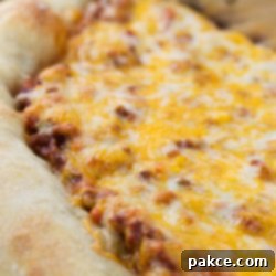 Hearty Sloppy Joe Pizza 2 Side view of a whole pizza with sloppy joe sauce covered with colby-jack cheese on a thick crust