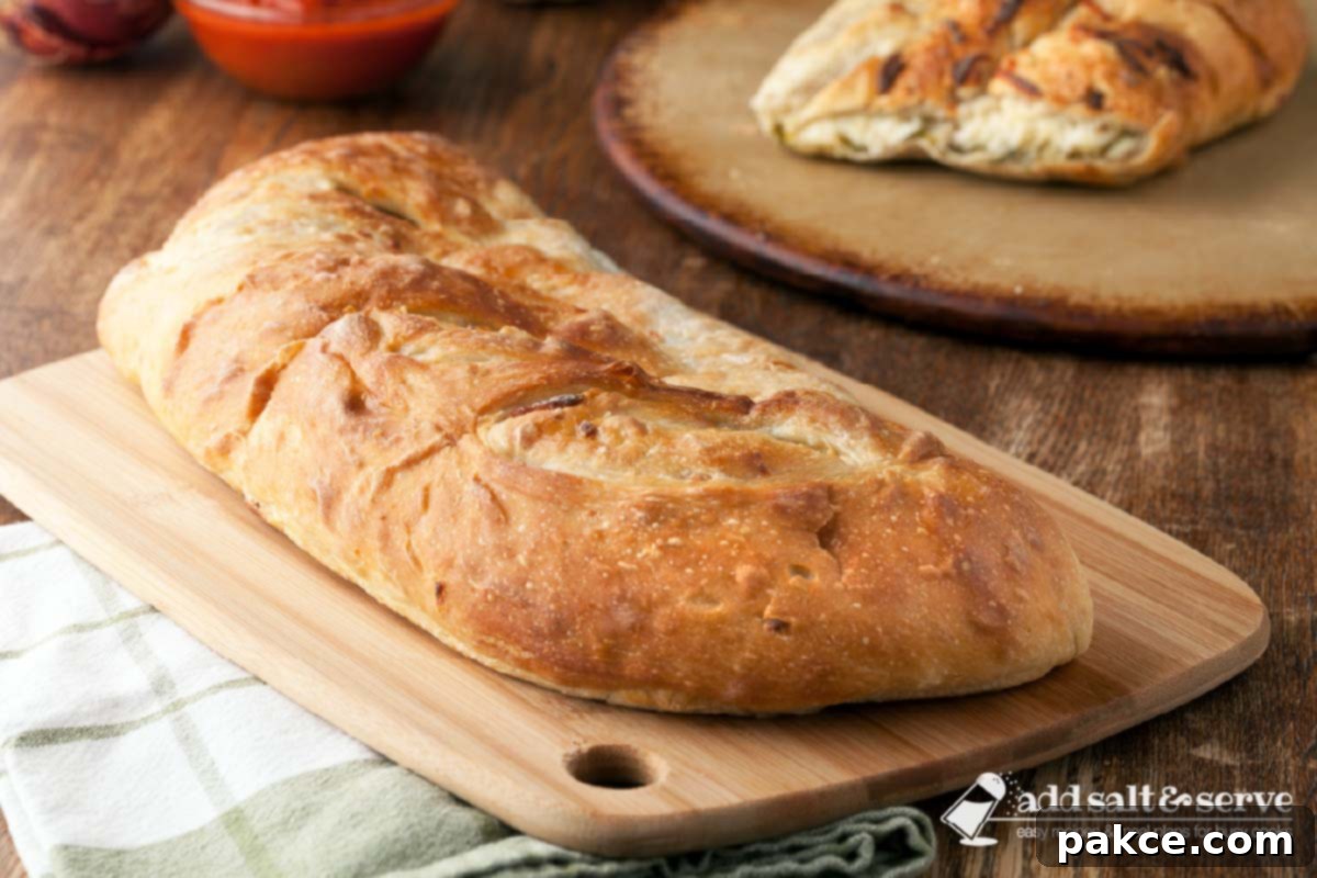 A freshly baked Vegetable Stromboli on a wooden cutting board, with a generous slice already cut, revealing the luscious, cheesy vegetable filling inside. Perfect for a family dinner or a crowd-pleasing appetizer.