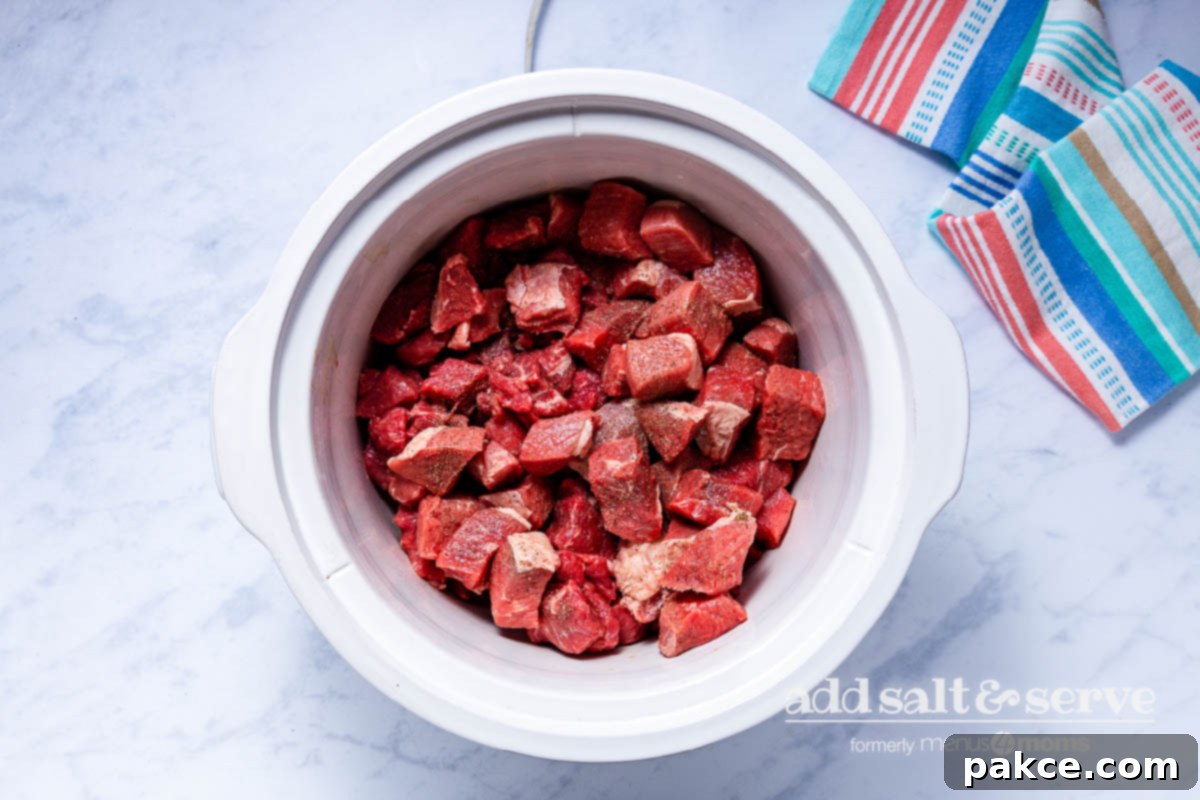 Effortless Slow Cooker Carne Guisada 3 Overhead view of beef in a crock pot for Carne Guisada.