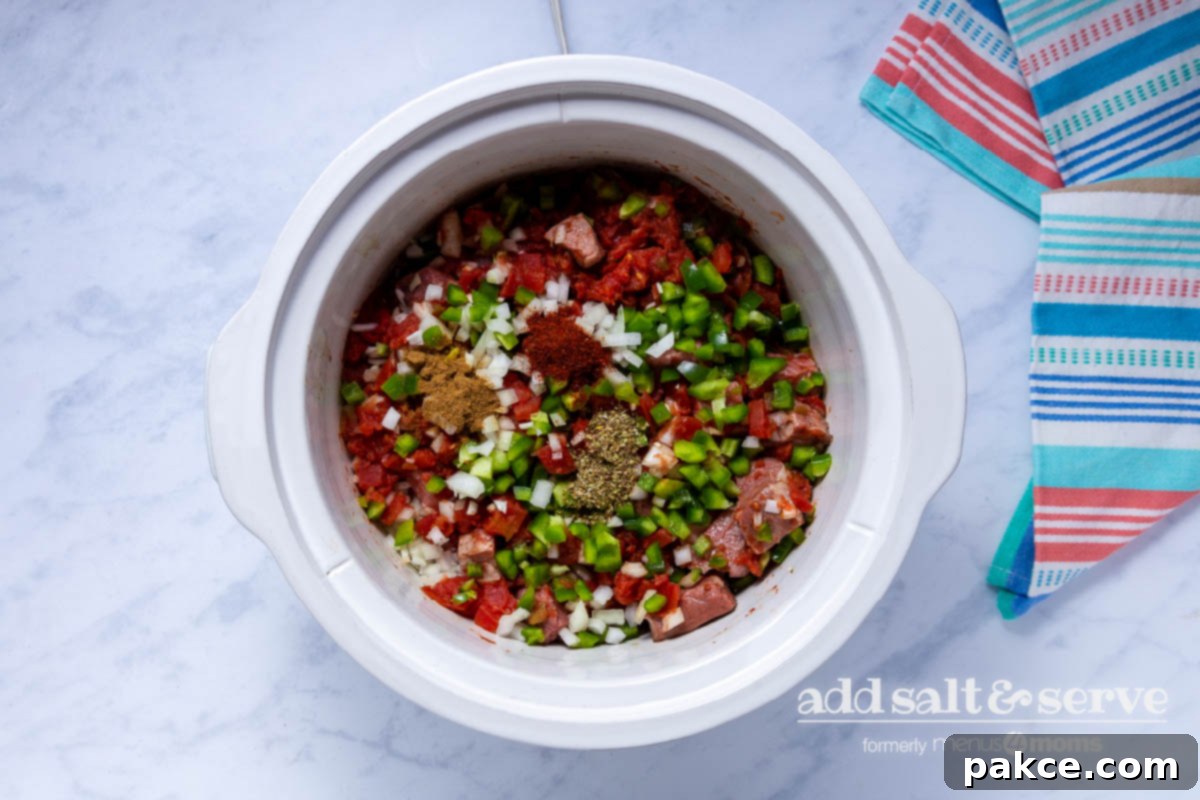 Effortless Slow Cooker Carne Guisada 6 Overhead view of meat, vegetables, and spices for Carne Guisada in a crock pot.