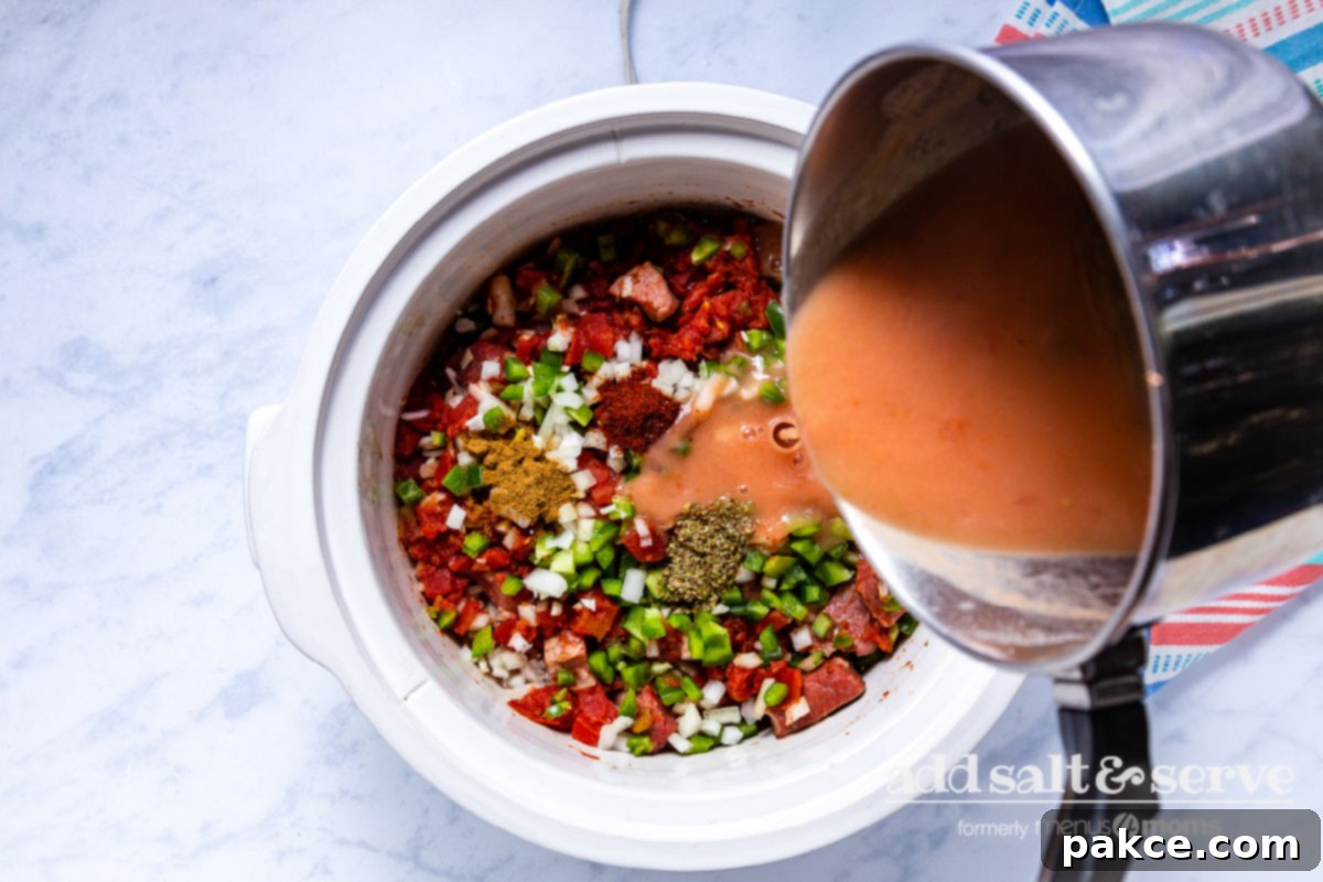 Effortless Slow Cooker Carne Guisada 7 Pouring thickened sauce for Carne Guisada over meat, vegetables, and spices in crock pot.