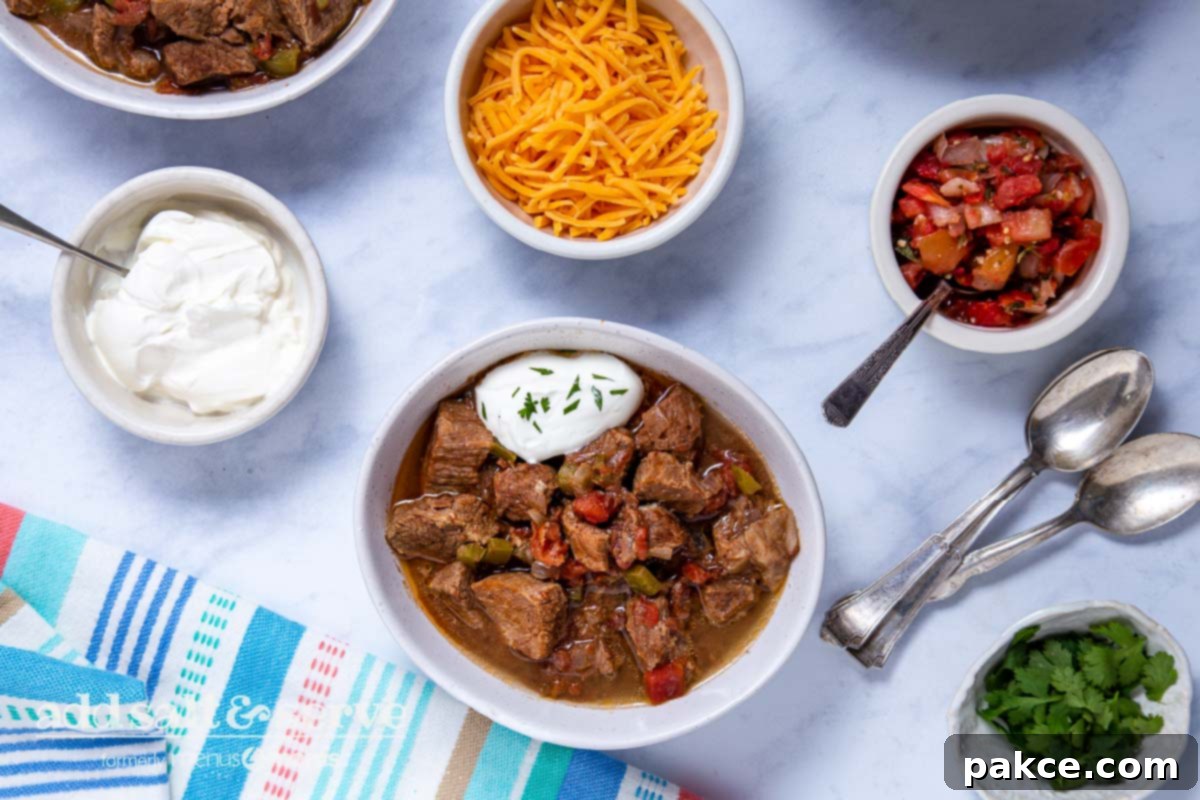 Effortless Slow Cooker Carne Guisada 8 Overhead view of Carne Guisada made in crock pot with garnishes in small bowls.