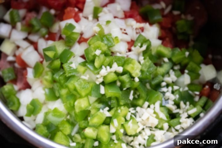 Carne Guisada: Add the tomatoes and green chilies, onion, green pepper, and garlic