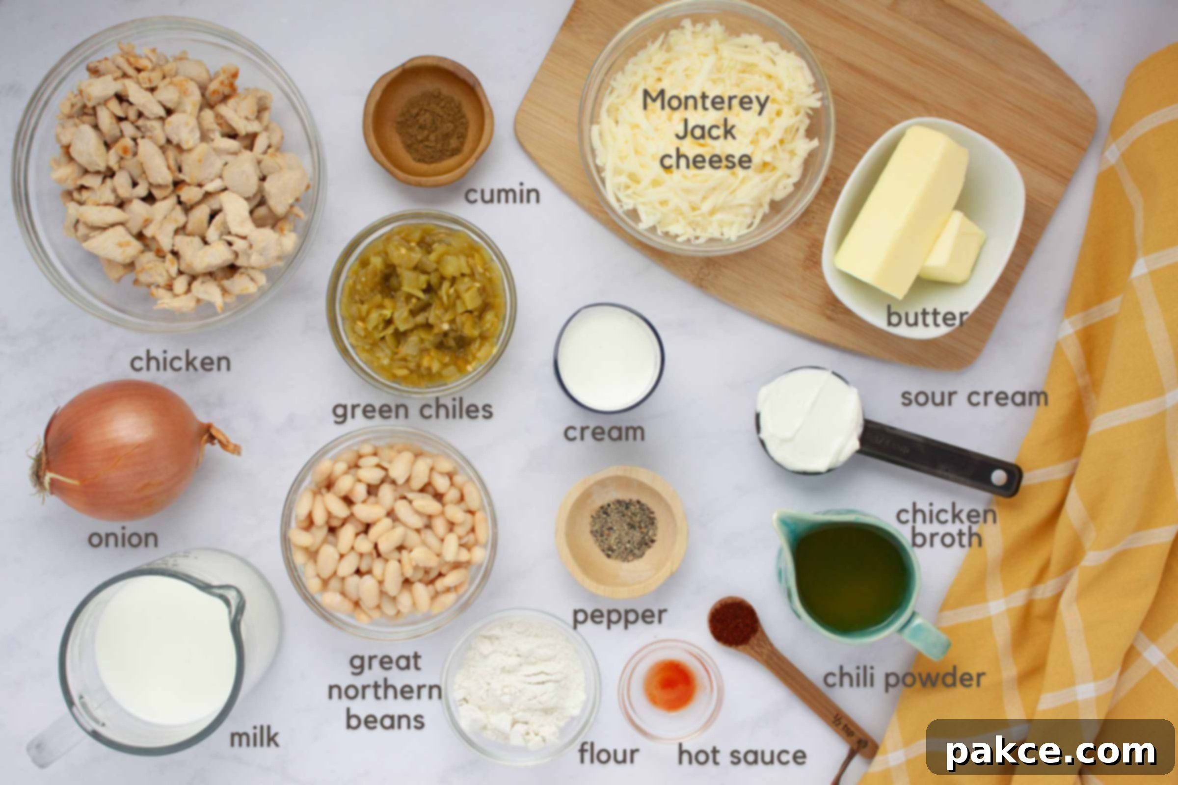 30-Minute Stovetop Creamy White Chicken Chili 3 Labeled image of ingredients for creamy white chicken chili: chicken, onion, milk, cream, chicken broth, great northern beans, green chiles, flour, butter,Monterey Jack Cheese. cumin, pepper, chili powder, hot sauce, and sour cream.