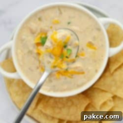 30-Minute Stovetop Creamy White Chicken Chili 8 A bowl of creamy white chicken chili garnished with cheddar cheese and cilantro and served with chips.