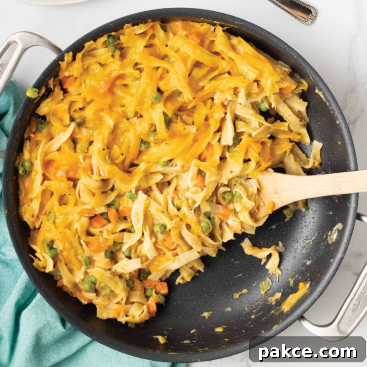 A golden-brown cheesy tuna casserole in a skillet, topped with melted cheddar cheese and fresh parsley garnish.