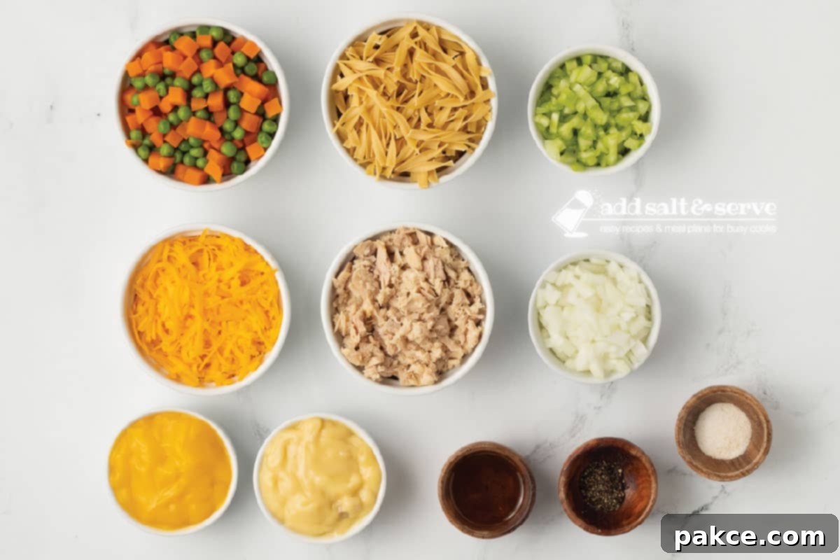 Golden Cheesy Tuna Delight 3 Overhead view of all fresh and canned ingredients for a cheesy tuna casserole spread on a wooden surface.