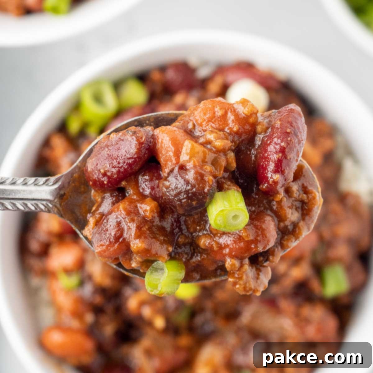 Spoonful of beef and beans garnished with green onion