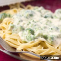 Creamy Broccoli Fettuccine Alfredo 3 Afredo sauce with broccoli over fettuccine on a clear glass plate with a fork