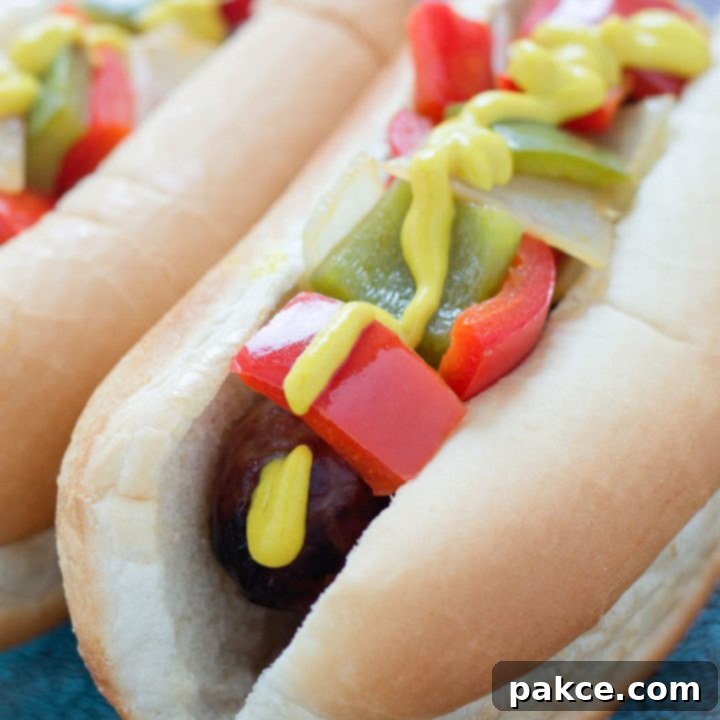 Bratwurst on a hotdog bun with mustard, diced red and green bell peppers and diced onions