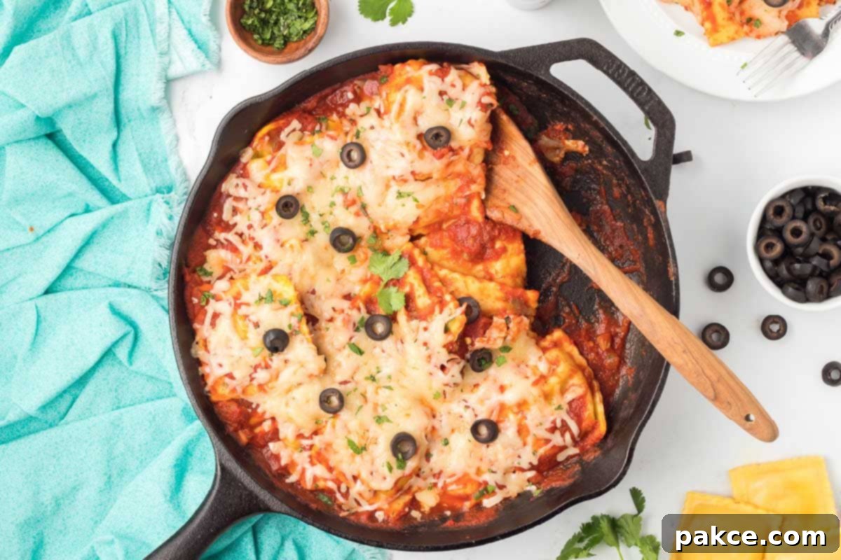 Fiesta Ravioli 6 Close-up of a cast iron skillet with perfectly cooked Mexican ravioli, mixed with salsa, herbs, and a rich tomato sauce, generously topped with melted Monterey Jack cheese, sliced black olives, and fresh cilantro sprigs, ready to be served hot.